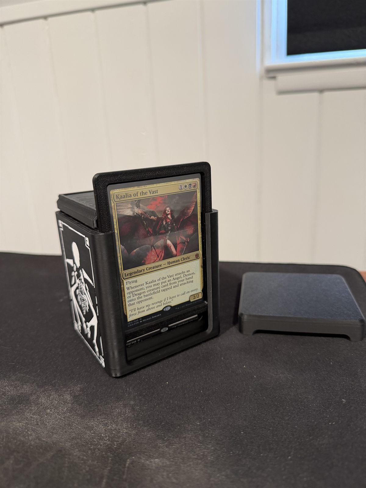 The deck box open with the lid off and a Magic card standing in the front display slot